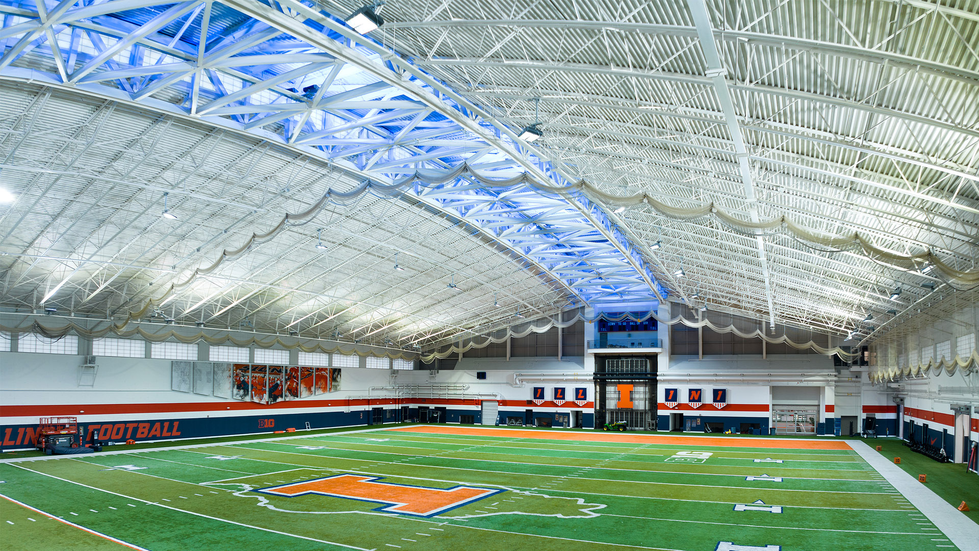 The University of Illinois Irwin Indoor Football Arena lit with new LED arena lighting. The center of the roof has a stripe of the teams color (blue) using Musco’s Show-Light ProVenue package with RGBW special effects arena lighting.