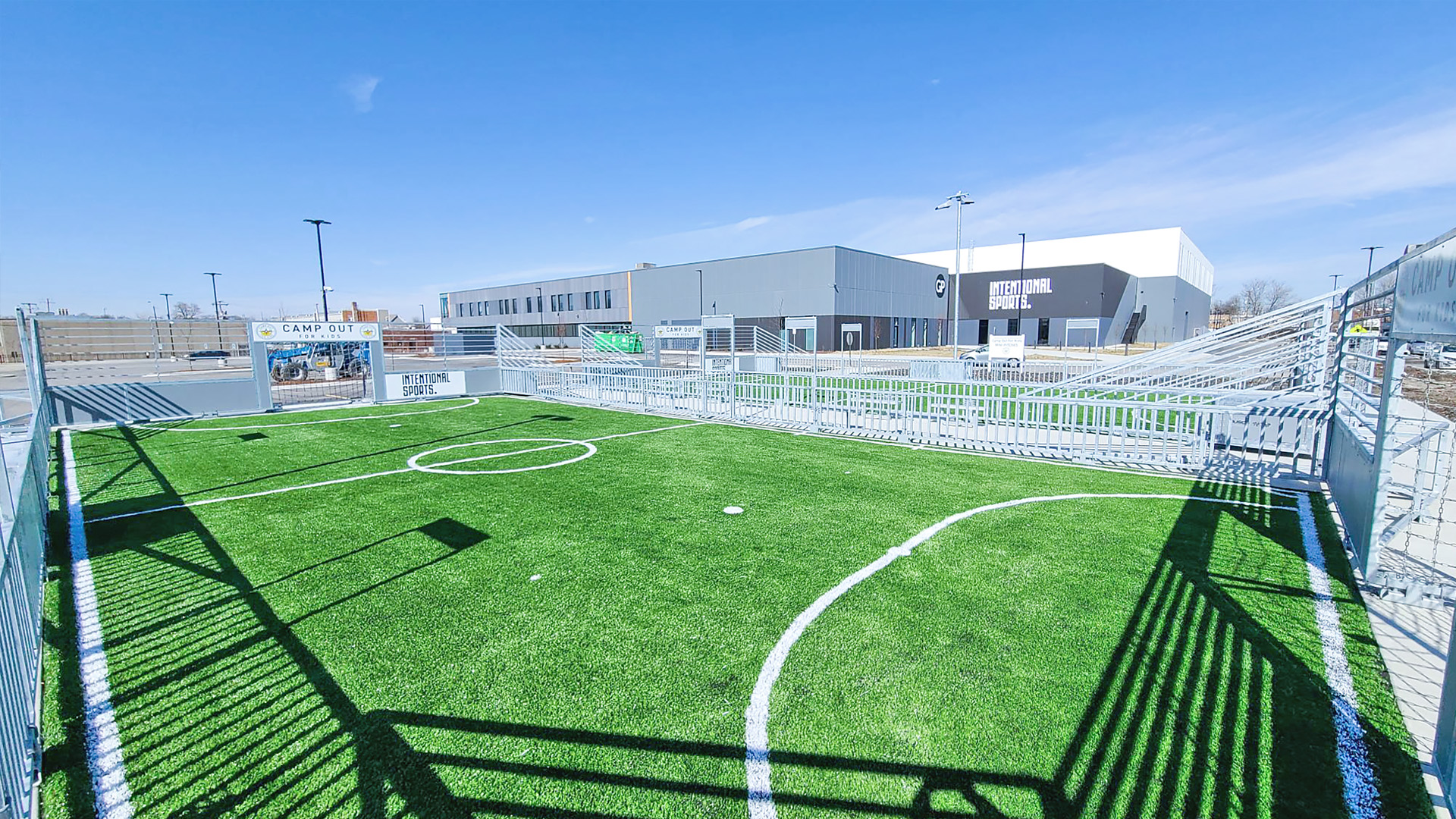 Musco Mini-Pitch system with turf surface and Intentional Sports campus in the background.
