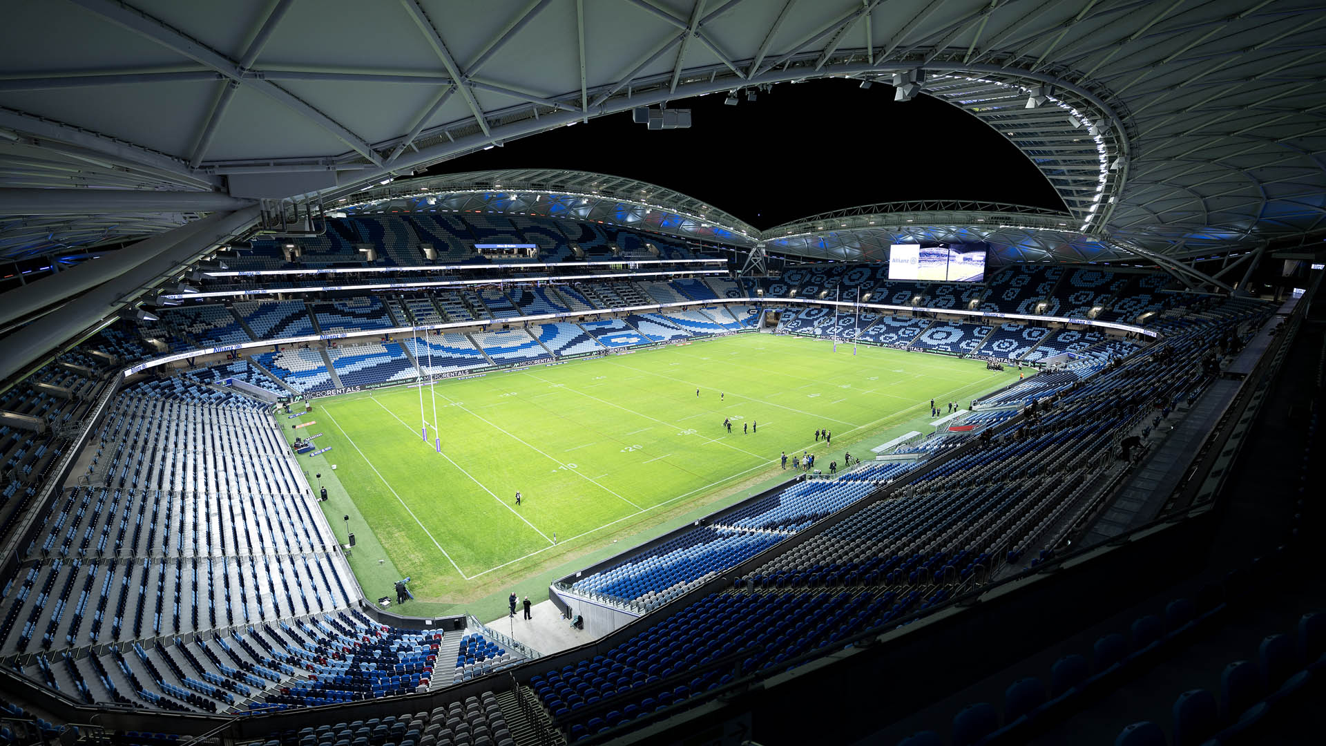 The field at Allianz Stadium in Sydney lit at night with new LED sports lighting as seen from the stands.