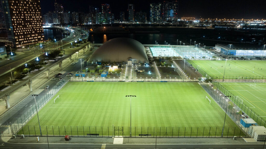 Soccer pitch (foreground) and Tennis courts (background) at Al Maryah Island lit at night after installing Musco LED lights.
