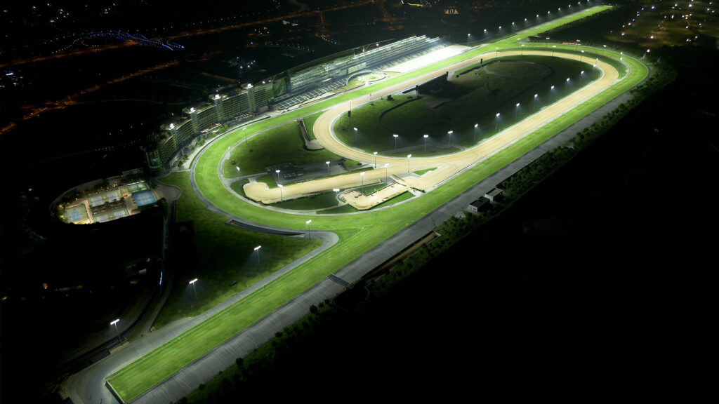 Overhead night view of the grass and turf tracks at Meydan Racecourse in after installing a new LED lighting system. Lighting remains on the turf and dirt horse tracks without spilling into the infield and surrounding areas.