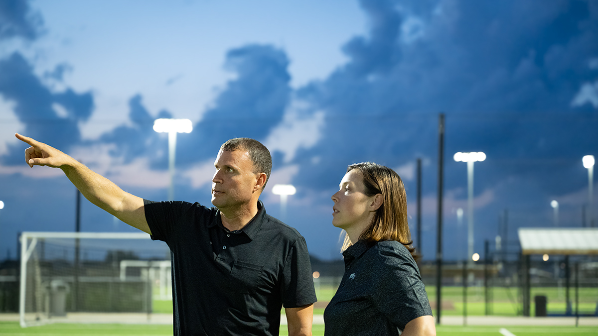 people standing underneath stadium lights
