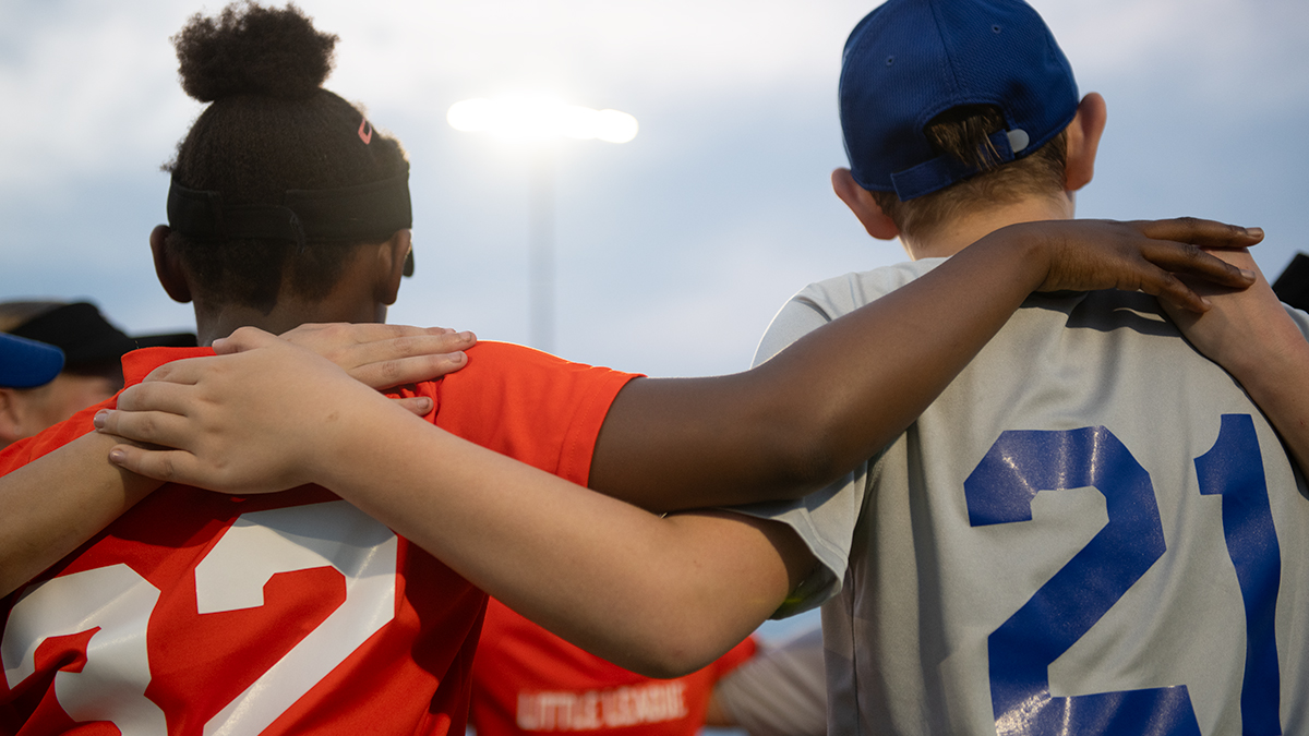 young baseball players linking arms together