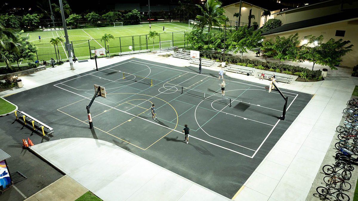 Pickleball being played on a basketball court with overhead lighting