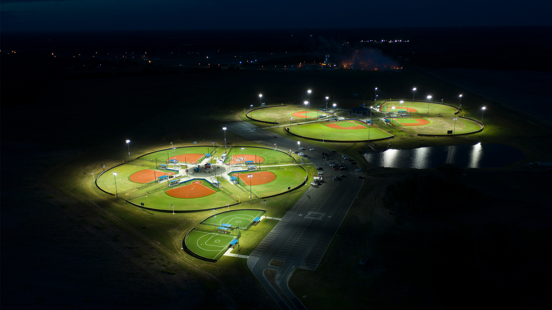 Multiple baseball diamonds at night lit up