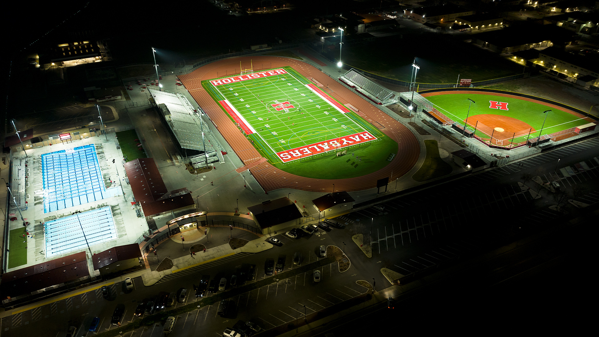 Hollister Haybaylers, side-by-side, swimming pool, football field and baseball field all lit up at night